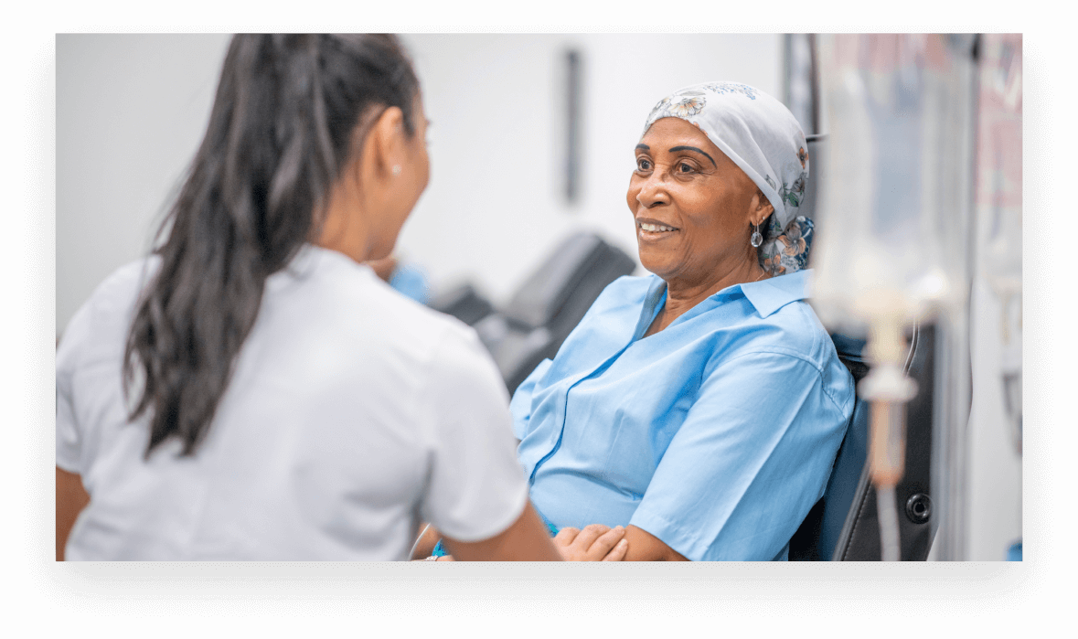 Women receives IV drip treatment from female nurse in blue scrubs